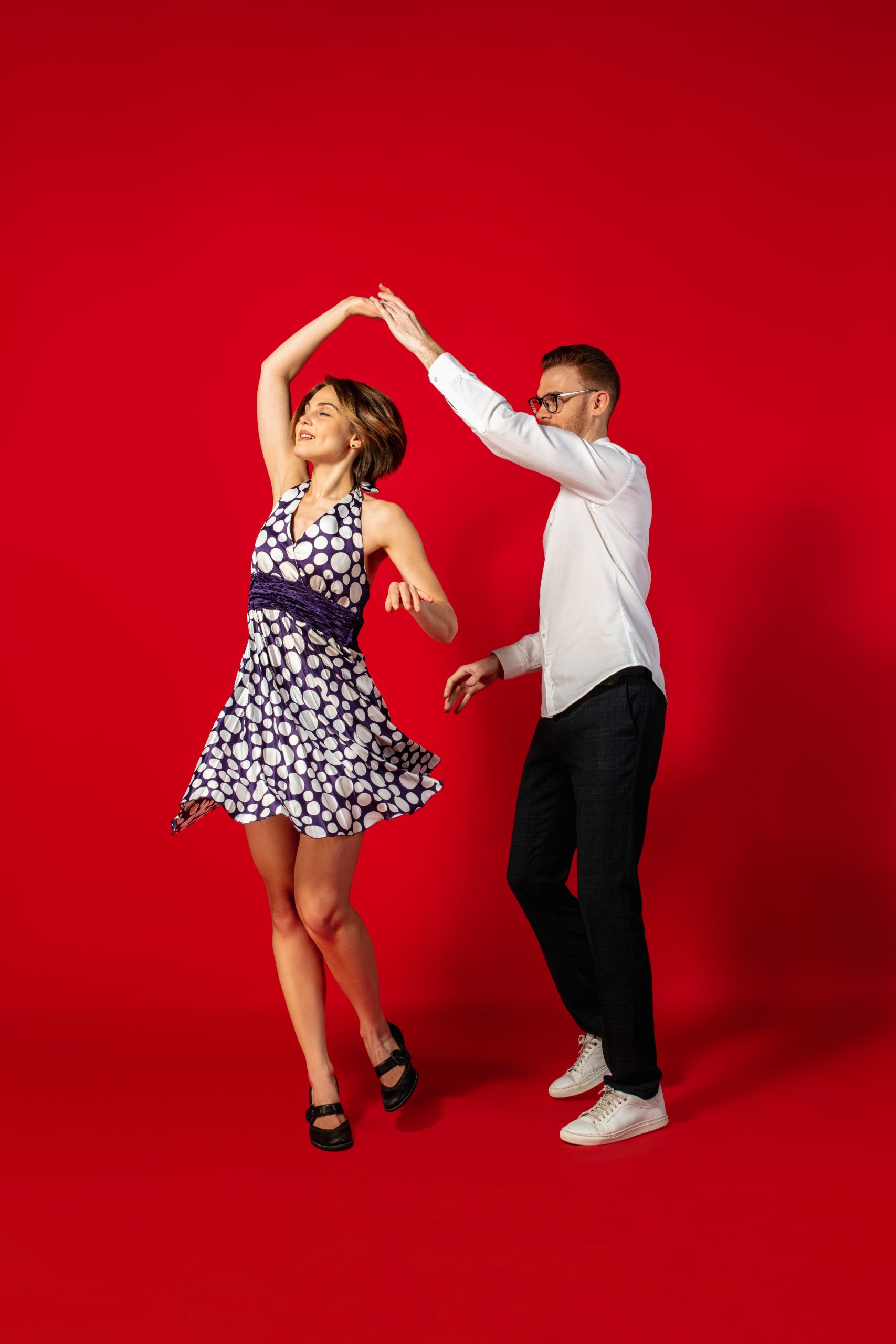 Rock n roll. Old-school fashioned young woman dancing isolated on red studio background. Artist fashion, motion and action concept, youth culture, fashion returning. Young stylish man and woman.